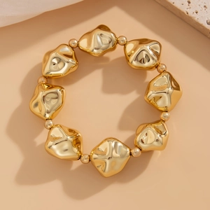 Vista macro de cuentas metálicas doradas irregulares y perlas espaciadoras para un look chic