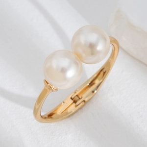 Macro shot of gold cuff bracelet with large twin pearls and polished striped texture