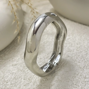 Macro detail of silver irregular wavy bangle featuring mirror polished finish and hinge