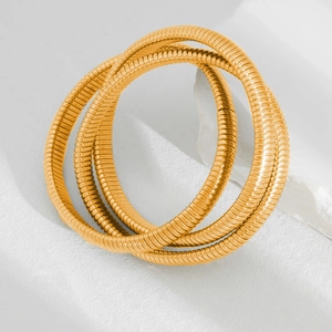 Close-up of golden multi-layer tubogas spiral bracelets set on marble background