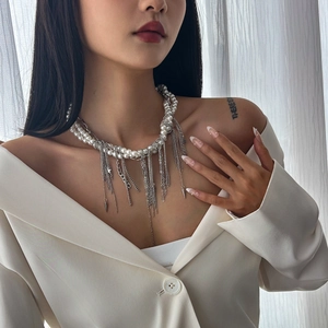 Détail du collier multicouche en métal argenté et perles avec pendentifs à pompons