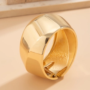 Polished gold wide cuff bracelet with a modern spring hinge design for a minimalist look