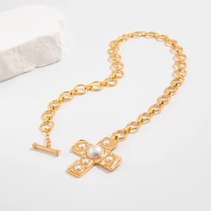 Detail of gold toggle clasp and pearl cross pendant on thick chain link necklace