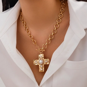 Golden liquid metal cross pendant necklace with pearls on a chunky chain worn by a model