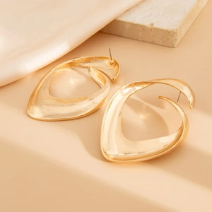Detail of gold abstract earrings with twisted metal texture and smooth brushed finish