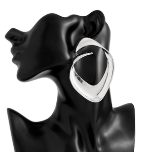 Detailed macro shot of sculptural silver bow earrings with irregular pleated metal texture