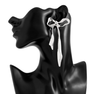 Detail of silver bow tassel earrings on a sleek black model display, elegant metallic design