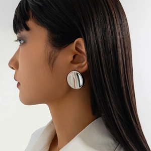 Polished silver large round stud earrings with metallic mirror finish worn by a model