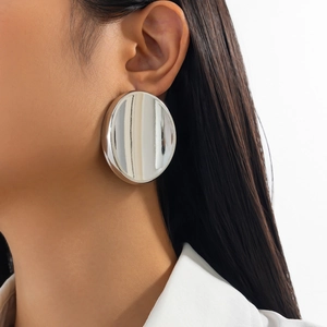 Close-up of a model wearing a large silver mirror-finish round earring with sleek metallic glow