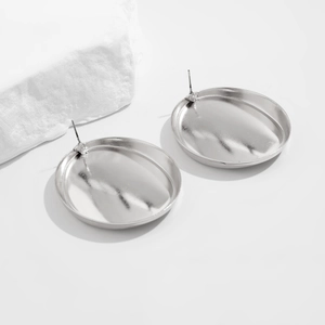Detailed view of silver bow stud earrings with textured metallic finish on white surface