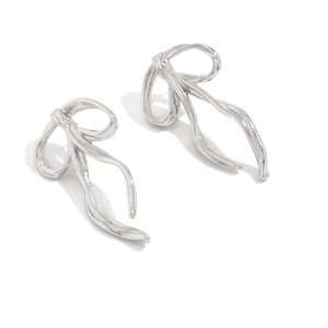 Macro view of silver ribbon bow stud earrings with polished metallic fluid texture