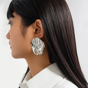 Close-up of a silver liquid metal earring with irregular folds worn by a model