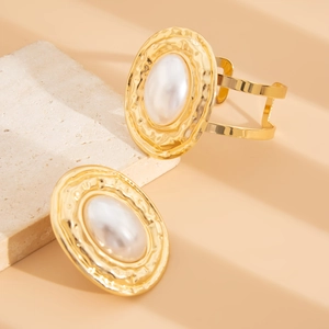 Dettaglio del bracciale rigido dorato martellato con intarsio di perla finta ovale