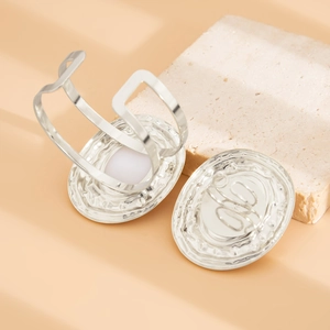 Dettaglio del bracciale aperto in metallo liquido argento con perla bianca e texture