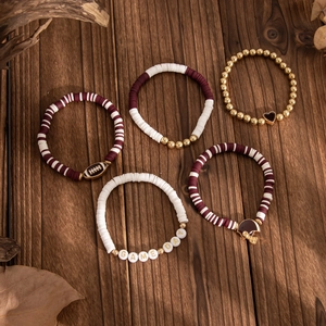 Detailed close-up of 5-piece burgundy and gold football beaded bracelet set on dark wood