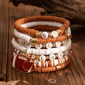 Close-up of stacked Heishi clay bracelets with Game Day lettering and rugby charms