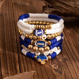 Close-up of stacked game day beads bracelets with football charms on rustic wood