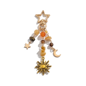 Detail eines Boho-Schlüsselanhängers mit goldenen Sonnenanhängern und Natursteinen