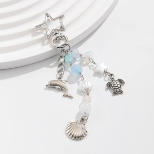 Detail of ocean-themed keychain featuring dolphin, turtle and shell charms with blue beads