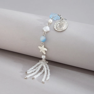 Macro detail of ocean theme keychain with white starfish, shell beads and tassel