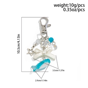 Detail view of a beaded keychain with a blue whale, white bow, and silver star charm