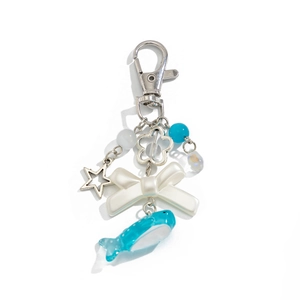 Detail of blue whale charm and resin bow on an ocean-themed seashell keychain