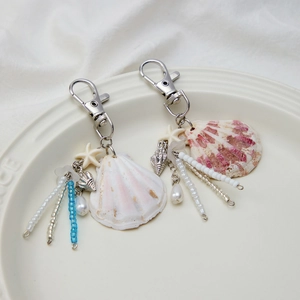 Detail of ocean-themed keychains with seashells and starfish on a ceramic tray