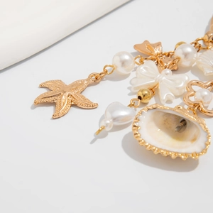 Close-up of ocean-themed starfish and shell charms with white pearls on a gold keychain