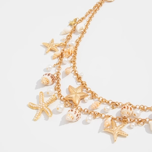 Detailed close-up of bohemian layered gold necklace with seashells and pearls