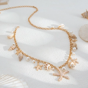 Detail view of bohemian gold chain with tiny starfish, seashells and pearl accents