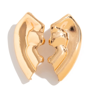 Dettaglio macro della trama metallica liquida irregolare sugli orecchini a cuore d'oro