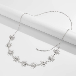 Detail of silver sun-face pendants on a bohemian waist chain over a white display stand