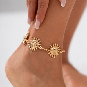 Detailed close-up of golden sun and moon face charms on an artistic fashion body chain