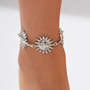Detailed view of silver sun and moon face charms on a vintage metal body chain jewelry