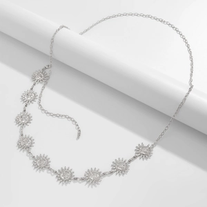 Detailed view of silver sun face pendants on a metallic bohemian waist chain