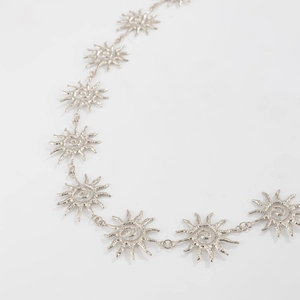 Macro detail of silver sun flower waist chain with textured metallic face pendants