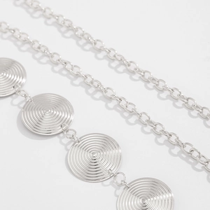 Close-up of silver metal waist chain featuring round pendants with spiral groove textures