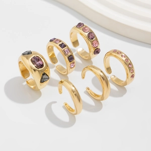 Detail van vergulde ringenset met kleurrijke edelstenen en verstelbare open ringen op gips