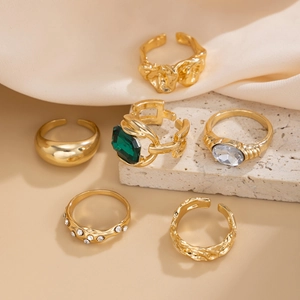 Detail van 6-delige vintage gouden ringenset met smaragd en zirkoon op stenen voet