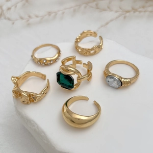 Detail van 6-delige gouden ringenset met smaragd edelsteen, lavatextuur en stras