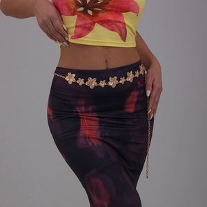Détail de la chaîne de taille fleurie dorée sur mannequin montrant la texture du métal