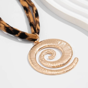 Macro shot of gold-plated spiral pendant and leopard print fabric ribbon on the necklace