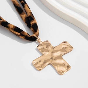 Detail of golden hammered cross pendant with a leopard print fabric necklace cord
