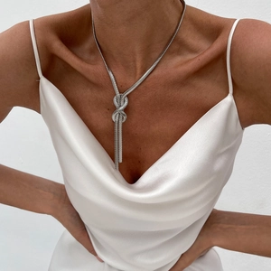 Silver flat snake chain necklace with an infinity knot and long fringe tassels on model