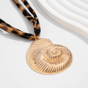 Macro view of gold shell pendant with leopard print fabric cord necklace