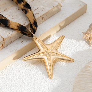 Detailed view of a gold starfish pendant on a stylish leopard print fabric necklace strap