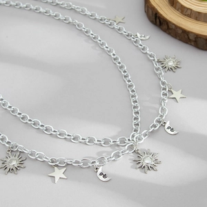 Detailed close-up of silver metal multi-layer chain with sun, star and moon pendants