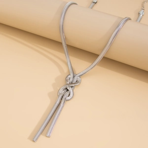 Detail of silver snake chain necklace featuring a central knot and dual tassel design