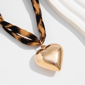 Detail of a large polished gold heart pendant with a stylish leopard print fabric lanyard