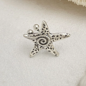 Makroaufnahme einer Vintage-Silber-Seestern-Ohrmanschette mit bionischen Texturen und Punkten